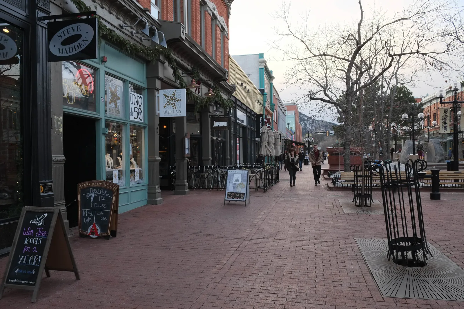 Brick storefronts and bare winter trees along the Pearl Street Mall in downtown Boulder